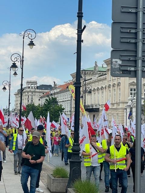 Marsz Solidarności — uczestnicy w kamizelkach odblaskowych z flagami Polski i Solidarności